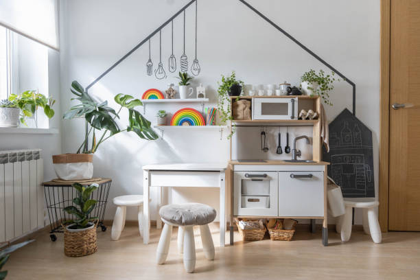 White childish kitchen interior early development playroom with Montessori wooden materials toy furniture. Kids cuisine with table oven faucet playing cooking food preparation domestic life imitation
