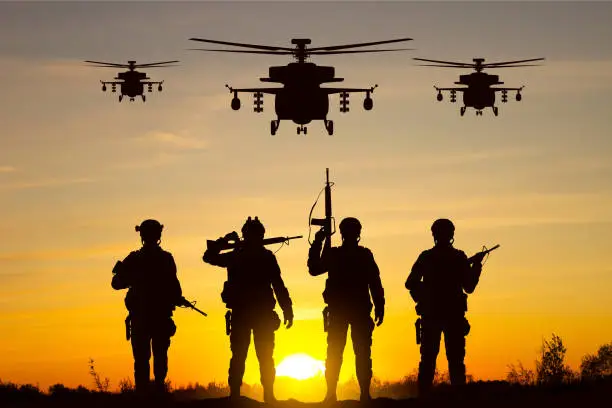 Photo of Silhouettes of soldiers with helicopters against the sunset