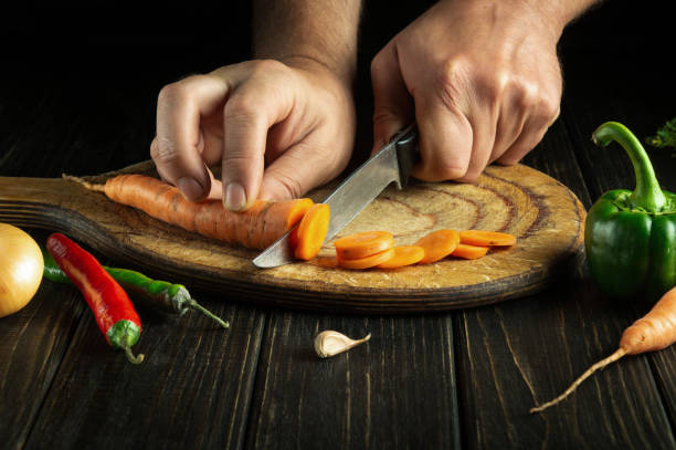 istock The chef cuts carrots into small pieces on a cutting board for preparing a vegetarian lunch or dinner. Set of vegetables on the kitchen table 1496351762