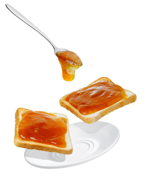 apricot jam pouring from spoon on bread toasts in saucer isolated on white