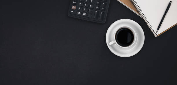 istock A cup of coffee, notepads, a calculator on a black background, top view. 1496354533