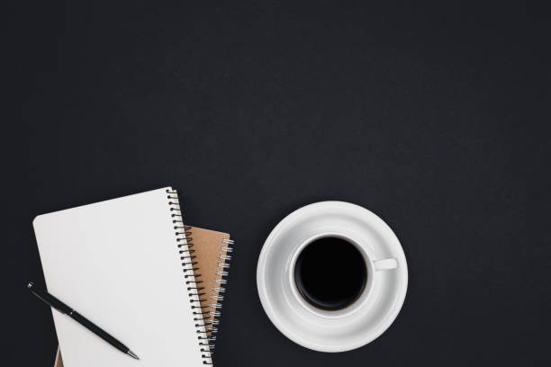 istock Cup of coffee and notepads on a black background, top view. 1496354538