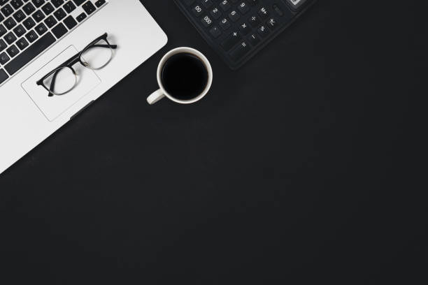 istock Flat lay black background with laptop, coffee cup and calculator, top view. 1496354550