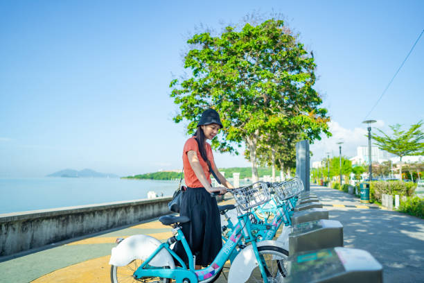 Asian girl renting shared bicycle near esplanade