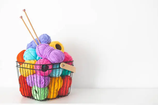 Photo of Cozy homely atmosphere. Female hobby knitting and Crochet. Yarn multicolor in a basket.