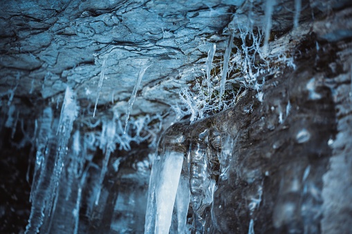 A close up shot of a rocky wall with several icicles hanging off of it