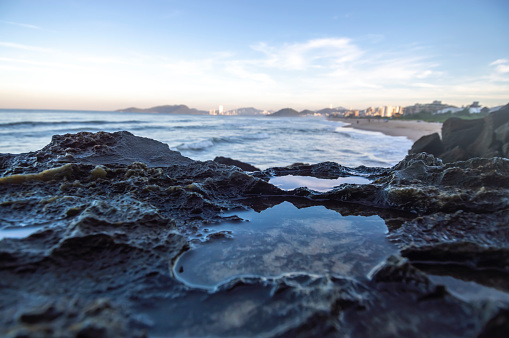 Wet stones by the waves of the sea and city of balneario camboriu-sc brazil in the background, concept of beach and tourism.
