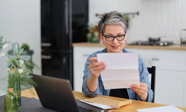 istock An elderly woman is glad that she is examining documents in the house. 1496359354