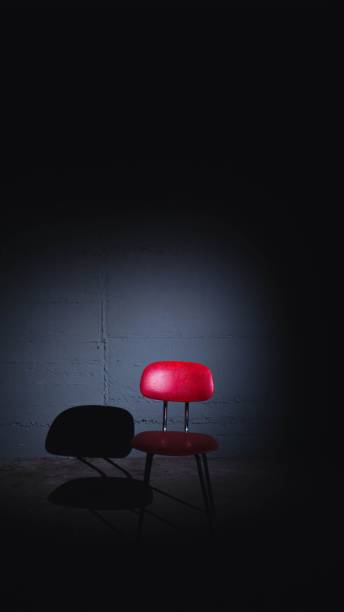 istock Red chair stands illuminated in a spotlight, casting an empty silhouette in a dark space 1496364103
