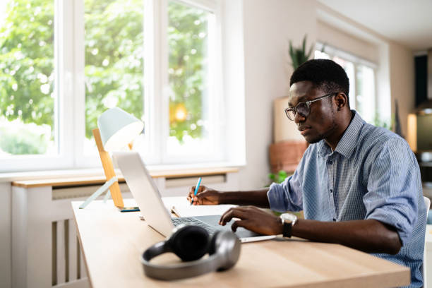 istock Modern male African-American freelancer working on laptop from home office 1496368413