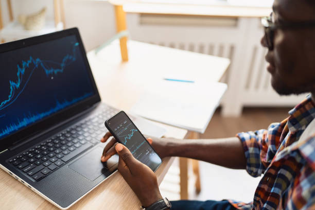 African-American male trader, follow the graph of stock market, while working from home office