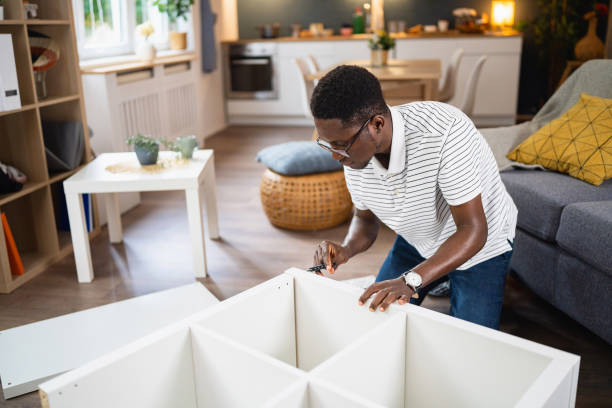 istock African-American man using electric screwdriver while assembling new furniture in the apartment 1496369451