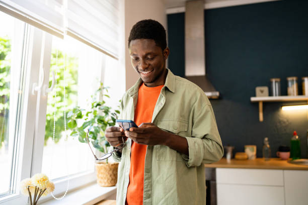 istock Young African-American man using mobile phone at home 1496369604