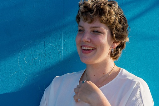 A portrait of a Caucasian woman posing against the blue wall