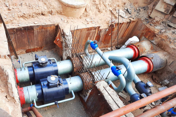 istock Pipe replacement. Installing PVC pipe conduit running through trench filled with dirt. Laying heating pipes in trench at construction site. 1496370823