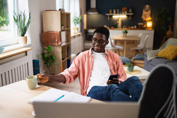 istock African-American man scrolling through internet on mobile phone, while taking a break from studying 1496371067