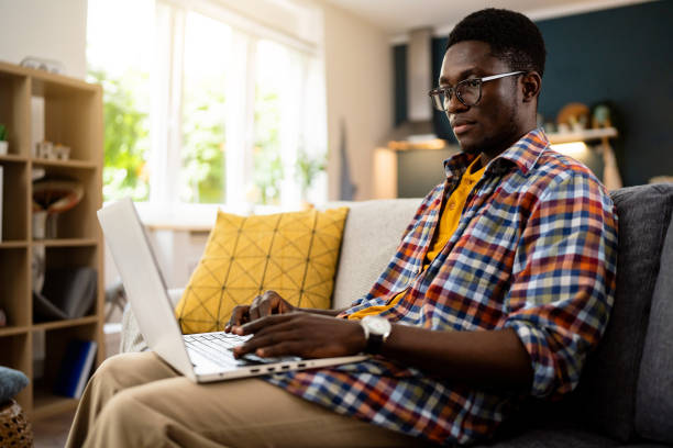 istock African-American man using laptop while sitting on the sofa 1496371531