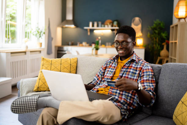 istock African-American man online shopping while sitting on the sofa 1496371631