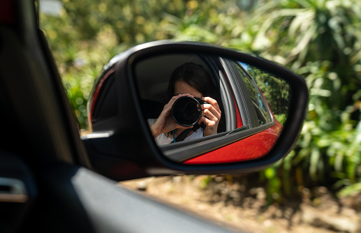 Woman taking a picture of herself in the car mirror