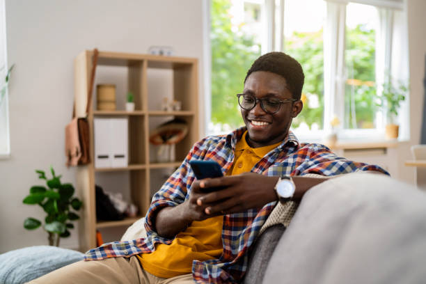 istock Young African-American man using mobile phone at home 1496372681