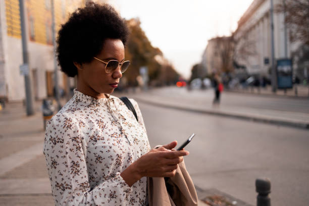 istock Side profile of an African female, wearing glasses, dressed nice, using a mobile phone. 1496372790