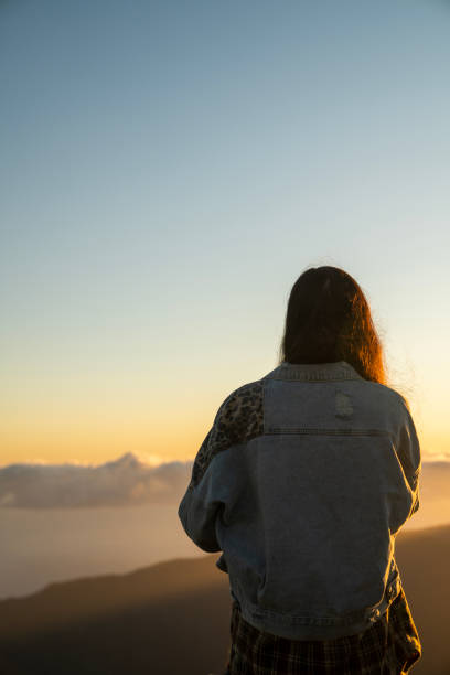 istock Woman watching a beautiful sunset over tall mountains vertical image 1496377264