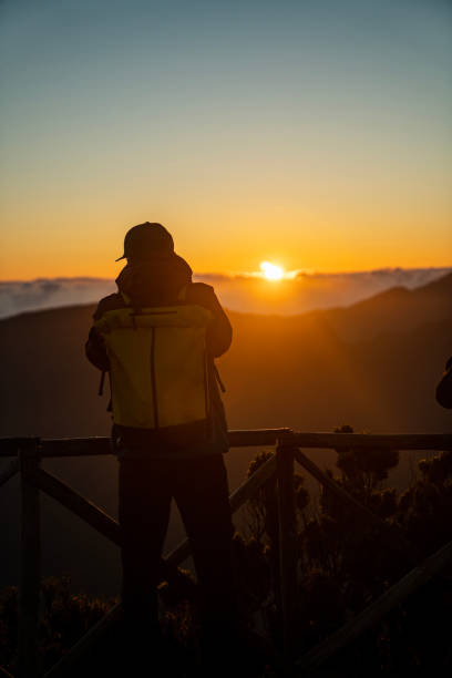 istock Hiker watching a beautiful golden sunset over tall mountains vertical image 1496377283