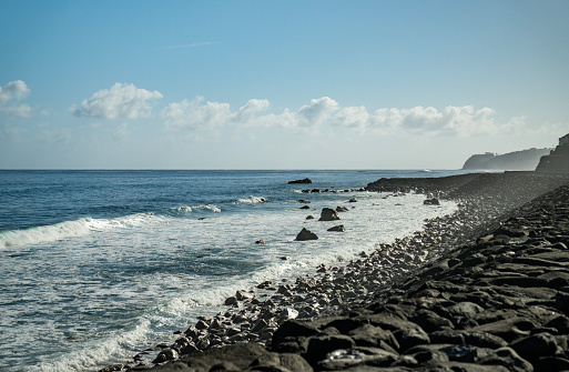 Pebble beach on the coastline in Madeira. Waves crashing