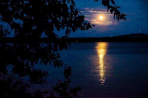Full moon and reflection over the Aylmer lake during a summer night in Beaulac-Garthby, Quebec.