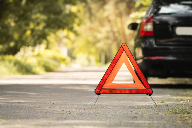 istock Red triangle, red emergency stop sign and black car with technical problems in the blurred background. Emergency stop of the car on the road. Safety procedure while having a vehicle broken down 1496383089