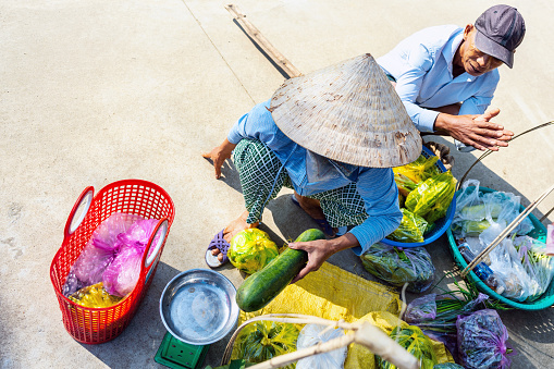 high angle view on senior woman and man selling vegetables on street in central vietnam village