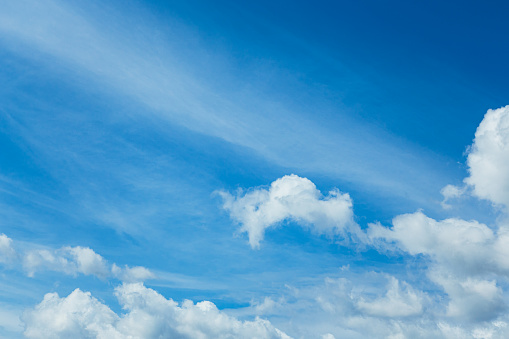 White clouds on a summer blue sky in cartoon style for background or wallpaper design. The whiteness of round clouds in a blue sky. High clouds in the sky.