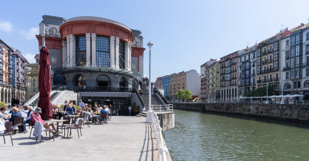 Bilbao Ribera market next to the Nervión river on a sunny day with people sitting on the terrace stock photo