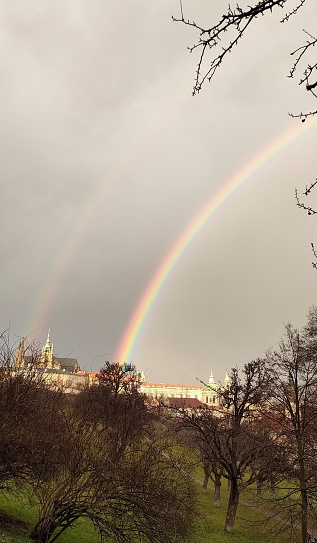 double rainbow photographed in the park below petrin. the cathedral appears right between the two arche