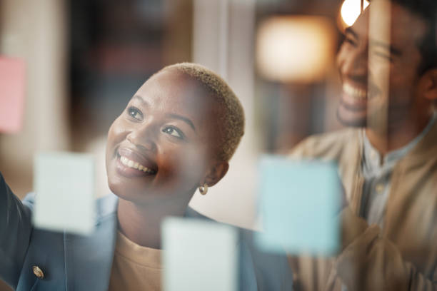 istock Teamwork, business people and creative idea for schedule, calendar or planning on sticky note in office. Thinking, brainstorming and woman with man for innovation, mission or collaboration on startup 1496394062