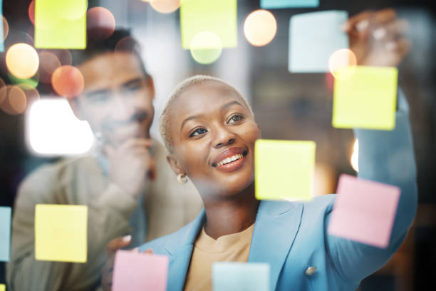 istock Planning, writing and business people in schedule, brainstorm or agenda, sticky note or innovation. Idea, partnership and happy black woman leader with solution goal, visual or problem solving answer 1496394075