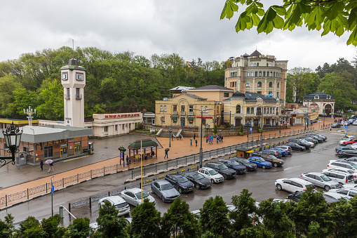 Kislovodsk, Russia - May 8, 2023: Vokzalnaya street view with the clock tower at Kislovodsk central railway station. Ordinary people walk the street on a rainy day