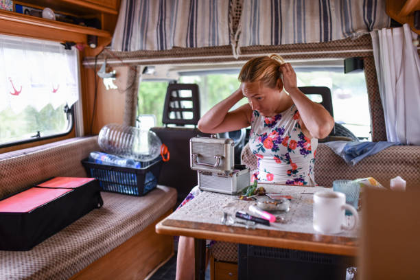 une femme blonde d’âge moyen fixe ses cheveux à l’intérieur d’un camping-car - beautiful hippie blond hair hair care photos et images de collection