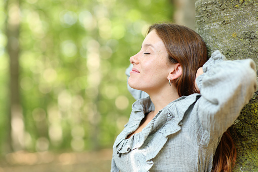 Woman resting leaining on tree in a park