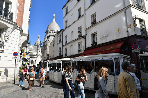 Paris, France-06 02 2023: Touristic train and tourists in a narrow street of Montmartre, Paris, France.