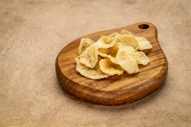 Dried slices of yacon tuber on a small wooden cutting board. Yacon contains inulin, a complex sugar, which promotes healthy probiotics. Superfood concept.