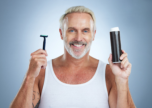 Senior man, razor and shaving cream for grooming, skincare or hair removal against studio background. Portrait of mature male holding shaver and foam creme for haircare, cosmetics or facial treatment