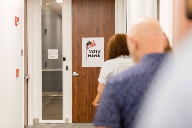 istock Rear view diverse people waiting to enter polling place 1496405365
