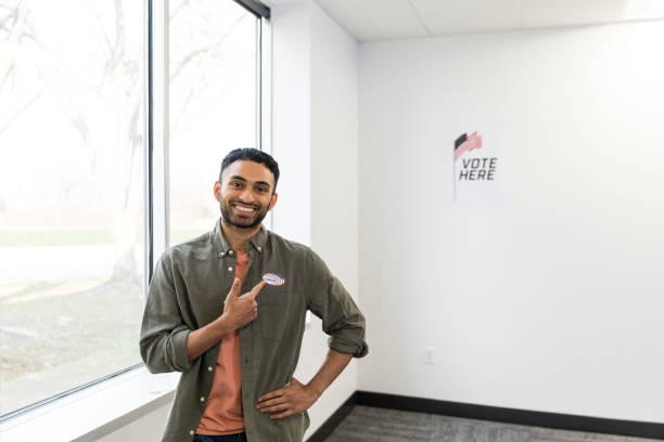 istock Young man smiles and points at voting sticker on shirt 1496405887
