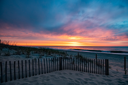 A colorful sunrise over the beach access path between the sand dunes in Ocean City, Maryland