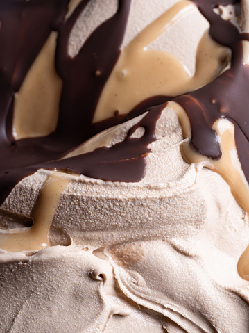 Frozen Toffifee flavour gelato - full frame detail. Close up of beige creamy surface texture of Ice cream covered with caramel and chocolate topping.