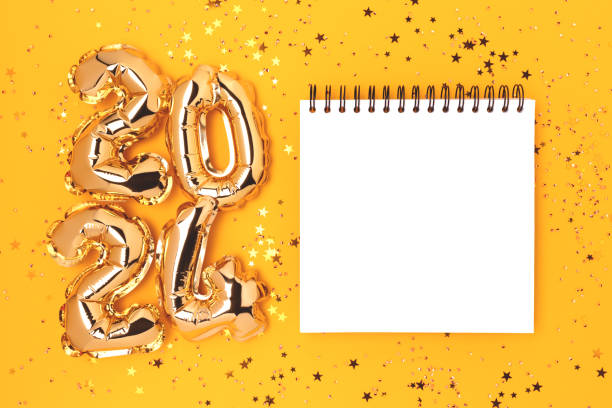 clean notepad mock up, glittering stars confetti and 2024 gold colored inflatable balloons. - determination new years eve list aspirations imagens e fotografias de stock