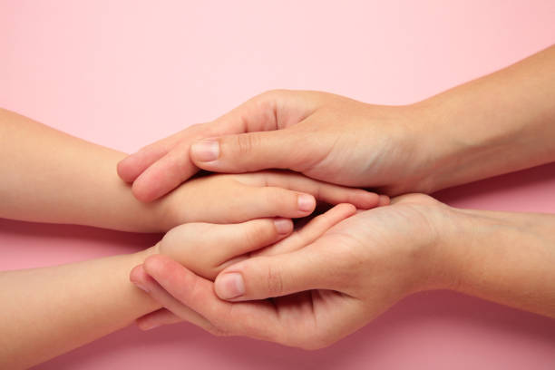 istock Mother holding daughter hands on pink background. 1496411577