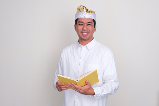Balinese man smiling happy while holding a book