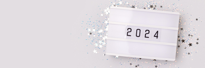 Banner with 2024 numbers and shiny silver stars confetti on a blue background. New Year festive concept.